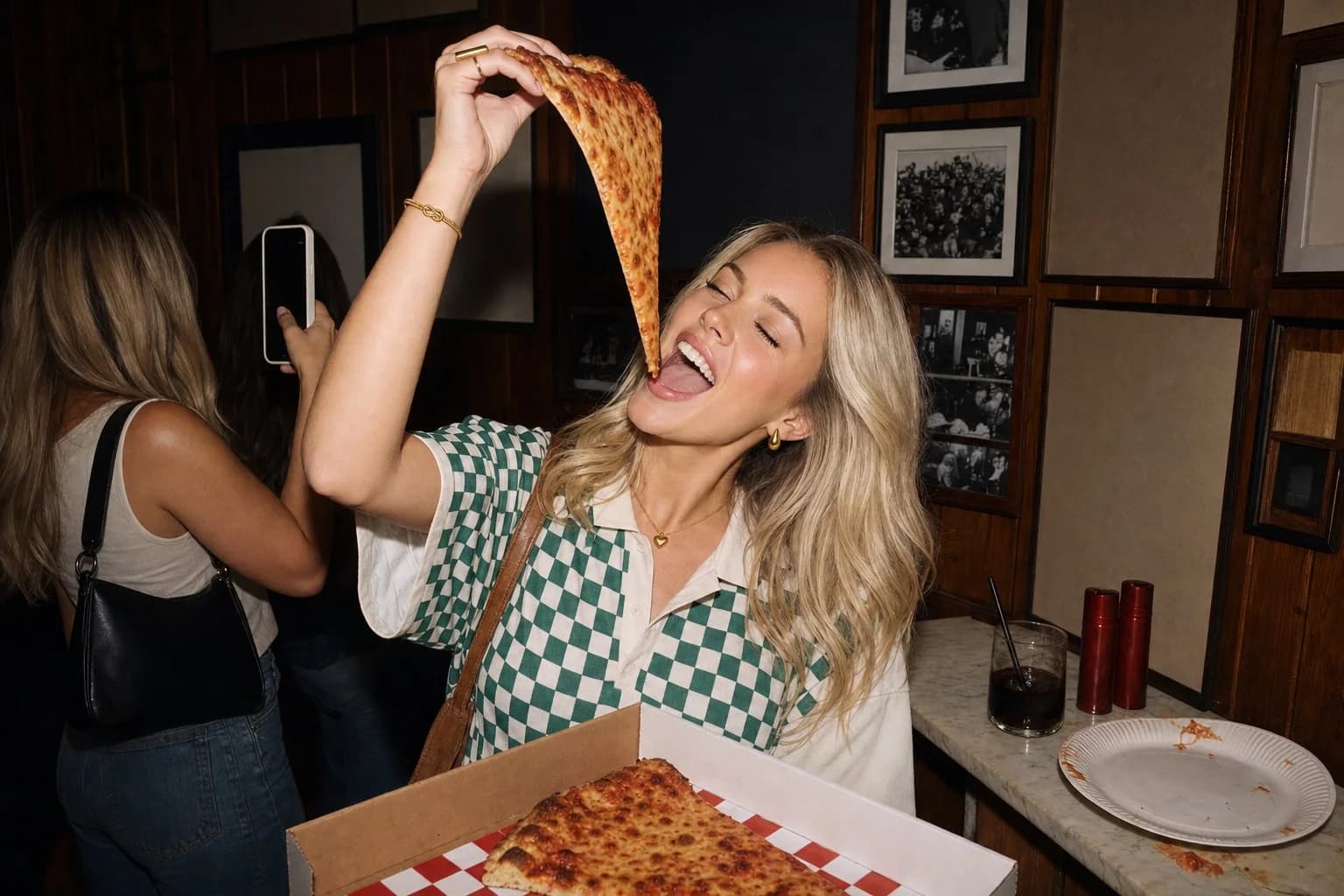 A slice of pizza held high in a pizza bar, wearing the Knot Bangle, Chunky Teardrop Studs and the Horizon ring