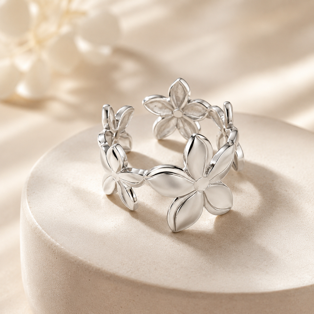 Silver flower,shaped earrings on a beige background