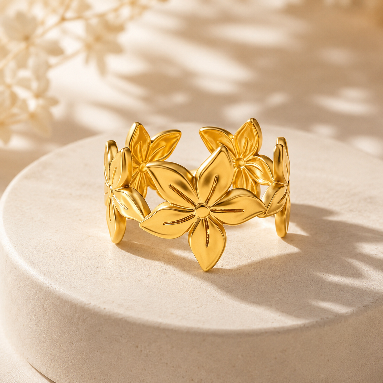 Gold floral bracelet on a beige surface with soft lighting