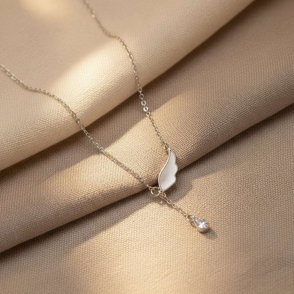 Silver necklace with l\angel wing pendant on a wooden plate