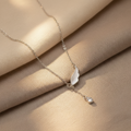 Silver necklace with l\angel wing pendant on a wooden plate
