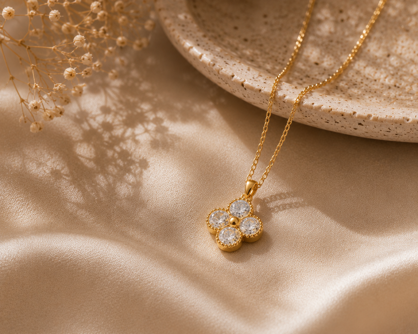 Gold necklace with a floral pendant on a beige fabric background