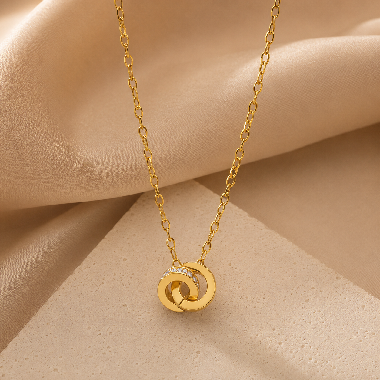 Gold necklace with a circular pendant on a beige fabric background