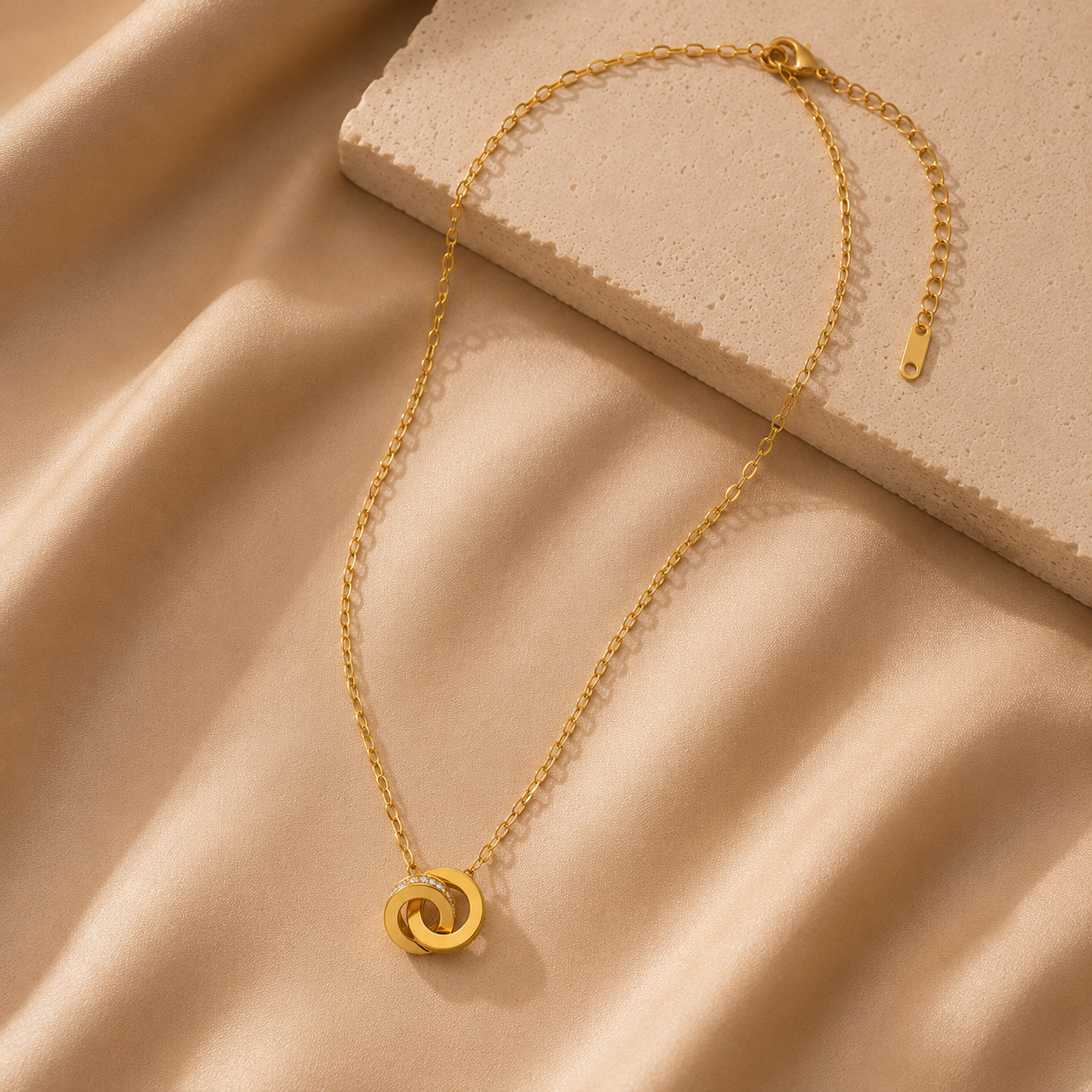 Gold necklace with a circular pendant on a beige fabric background