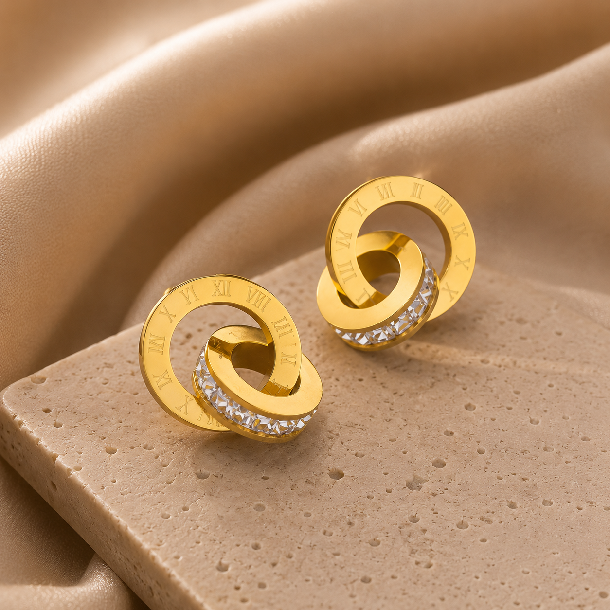 Gold earrings with circular design and embedded stones on a beige fabric background