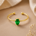 Gold bracelet with a green gemstone on a beige fabric background