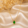 Gold necklace with a green gemstone on a beige fabric background