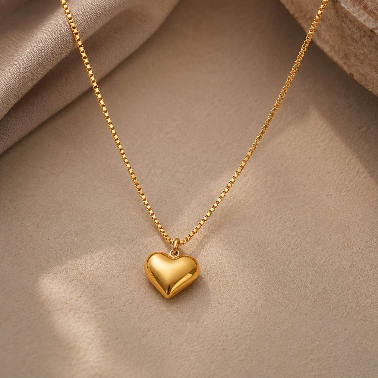 Gold heart,shaped pendant necklace on a beige fabric background