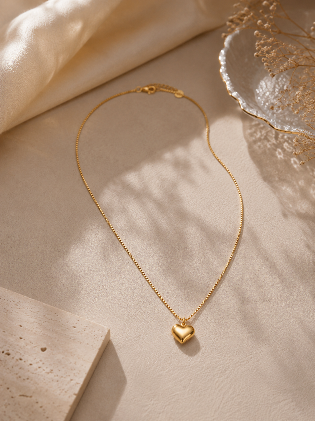 Gold heart,shaped pendant necklace on a beige surface