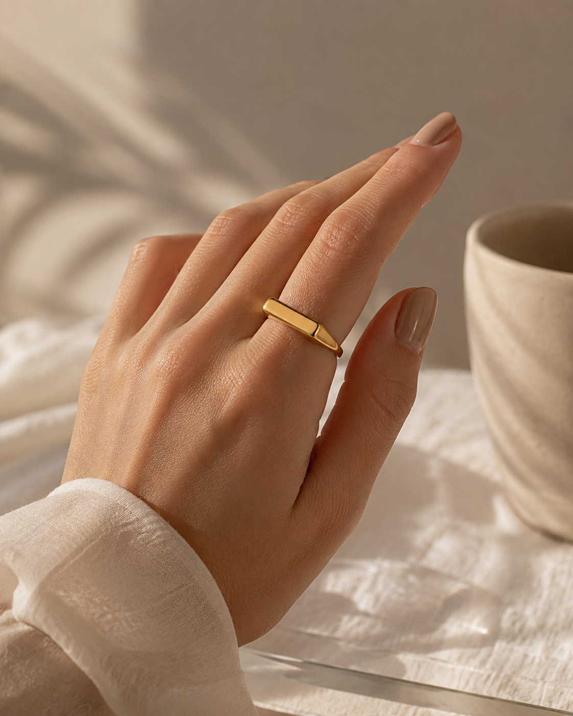 Hand wearing a gold ring with a neutral background
