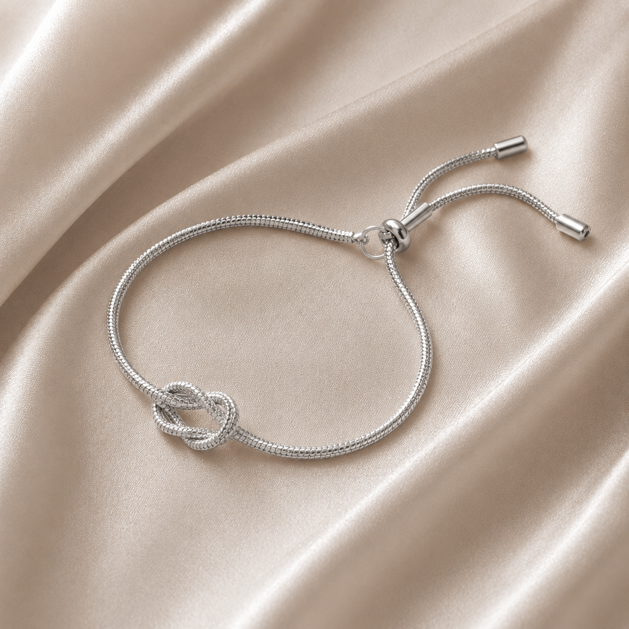 Silver bracelet with a knot design on a beige fabric background