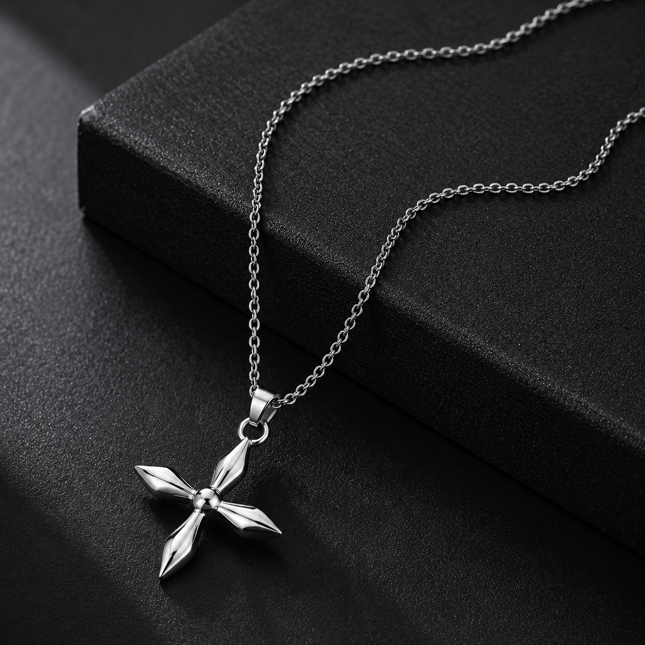 Silver cross pendant necklace on a black surface