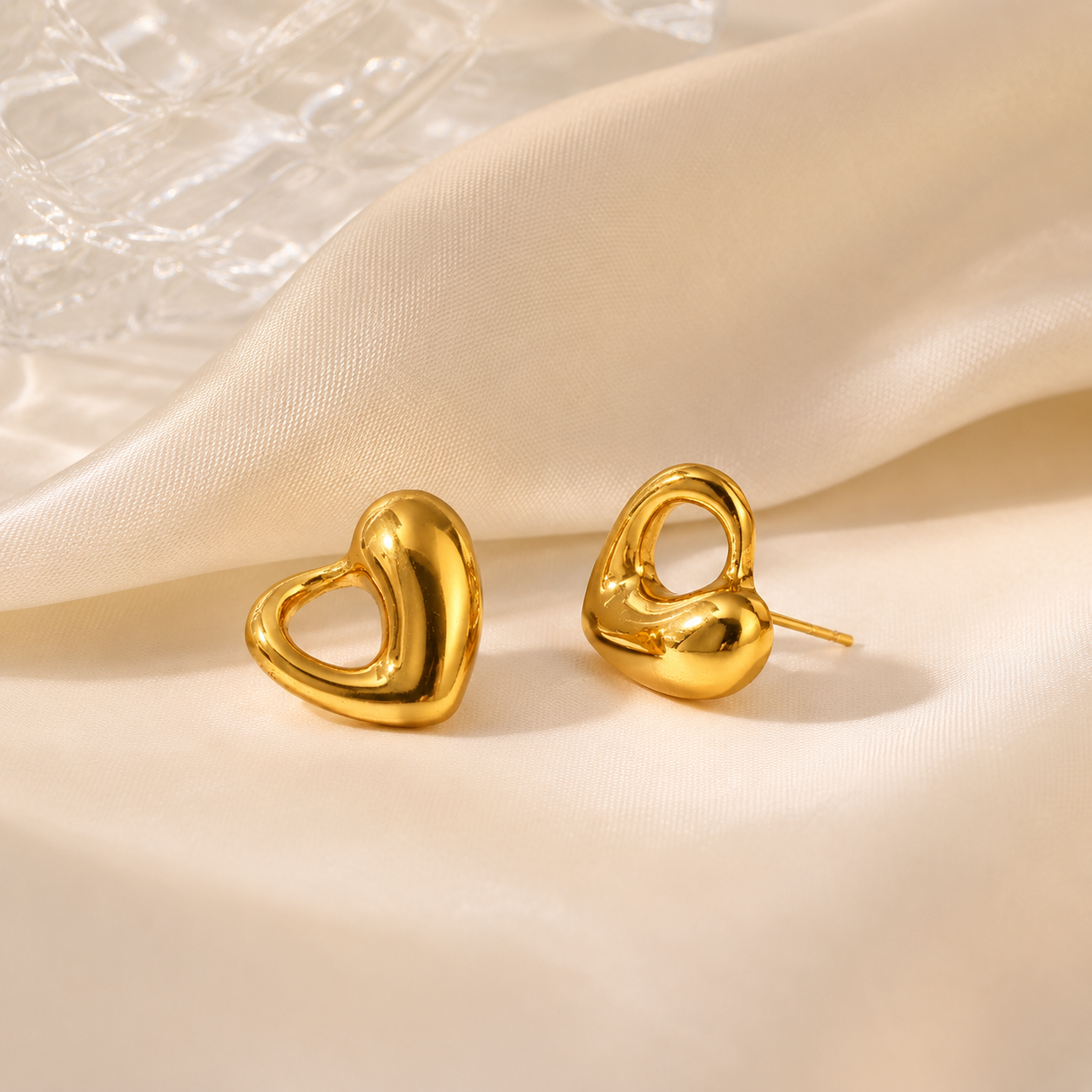 Gold heart,shaped earrings on a beige fabric background