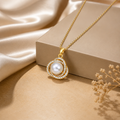 Gold necklace with a pearl pendant on a beige surface