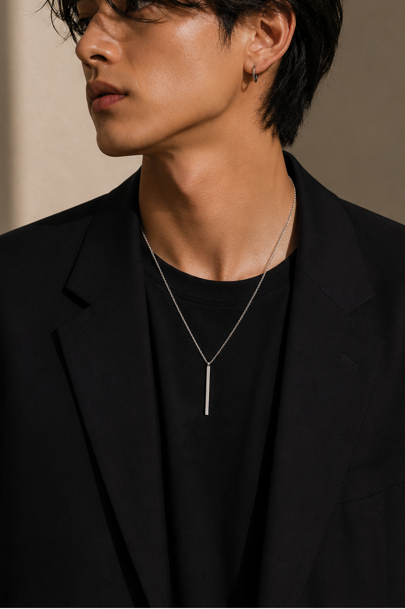 Person wearing a black suit style silver chain and pendant simple rectangle design