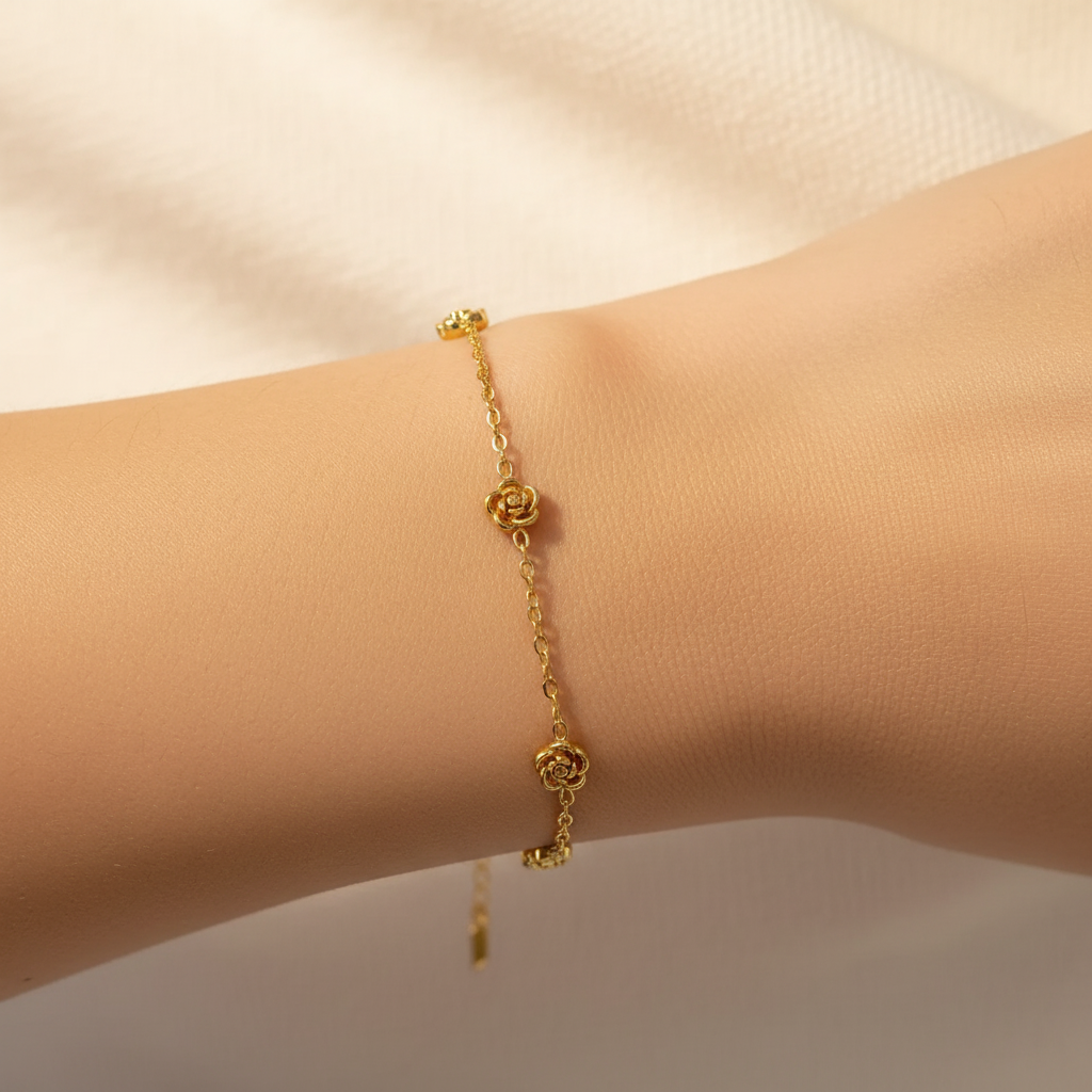 Gold bracelet with rose,shaped charms on a wrist against a neutral background