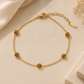 Gold bracelet with floral designs on a beige background