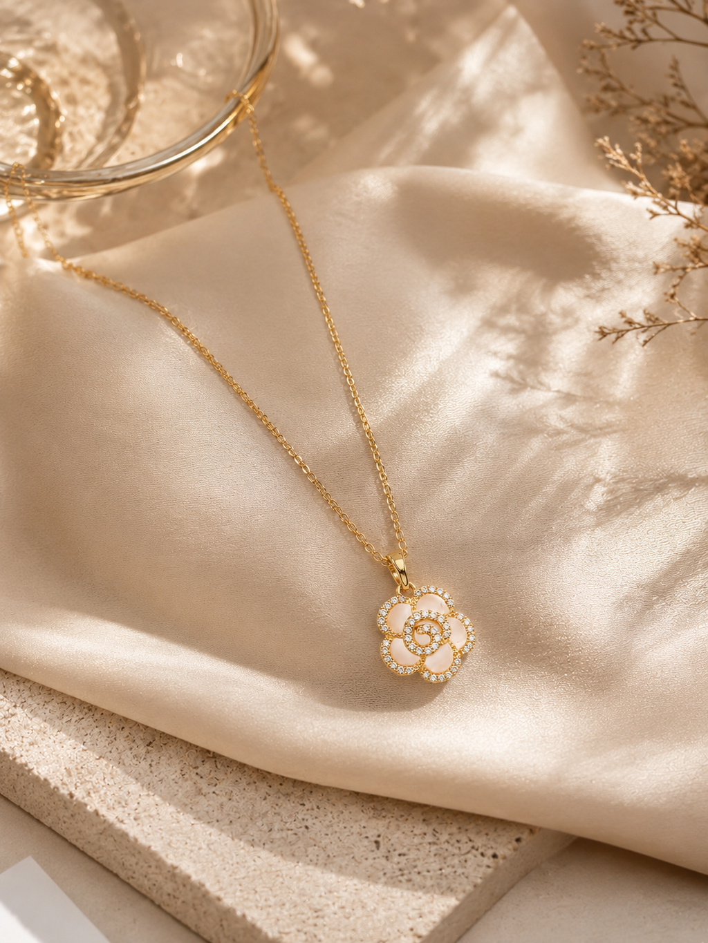 Gold necklace with a floral pendant on a beige fabric background